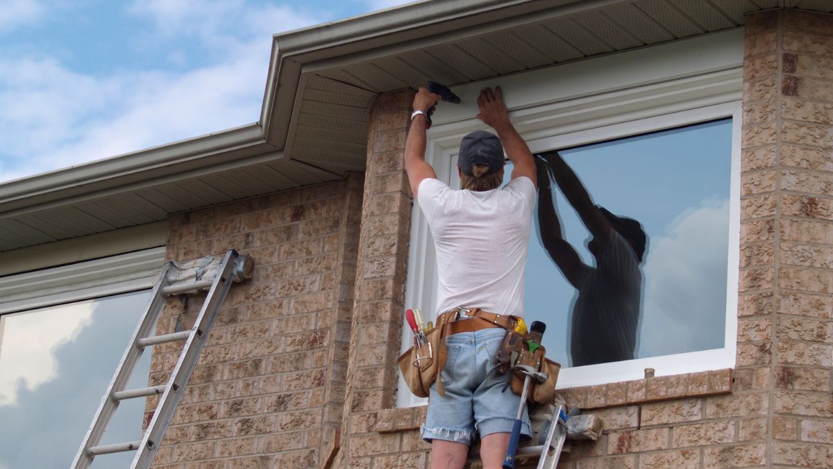 A man repairs a window, addressing common draft issues in Illinois homes before the winter season.