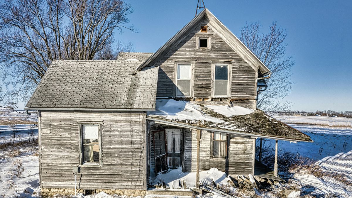 Abandoned House Covered in Snow in a vast, empty terrain - Emergency Roof Repairs in Winter