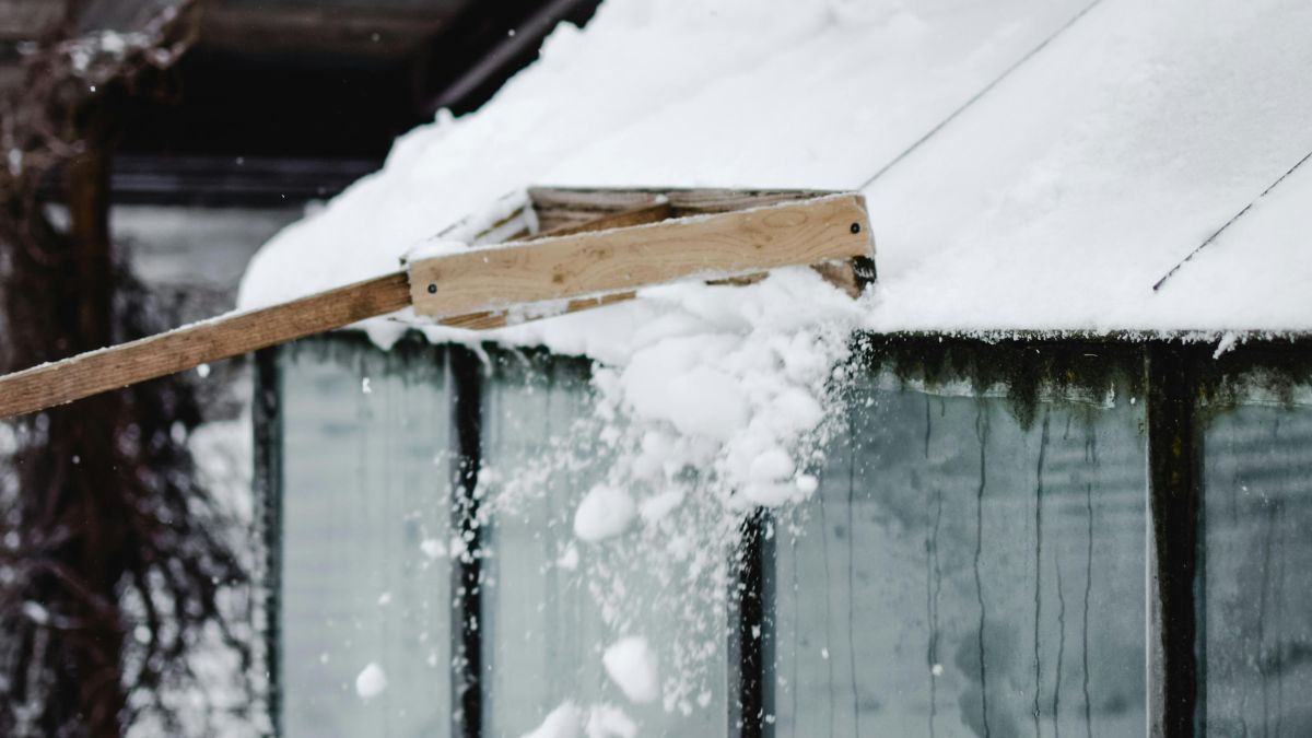 A Person Shoveling Snow off a Roof - Winter Roof Maintenance