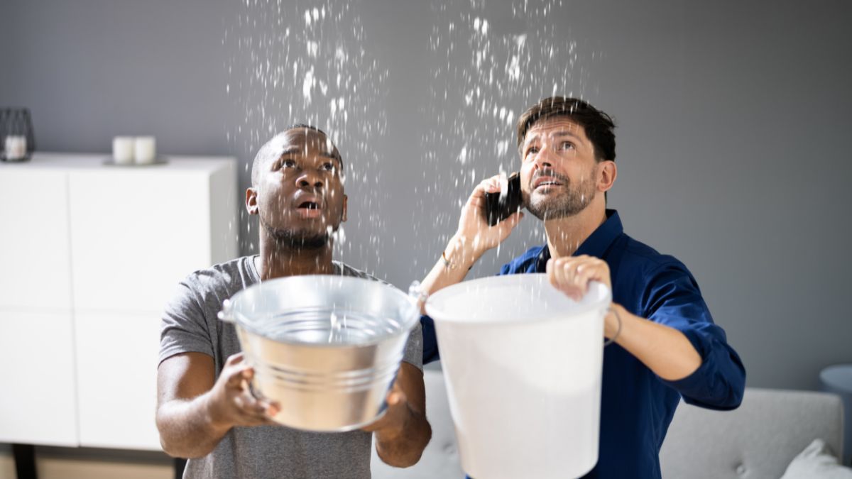 Two men with buckets conversing on the phone, focusing on crucial strategies for Illinois homeowners to prevent winter roof leaks.