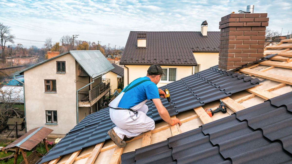 A man using a hammer on a roof, emphasizing the need for urgent repairs to prevent winter damage.