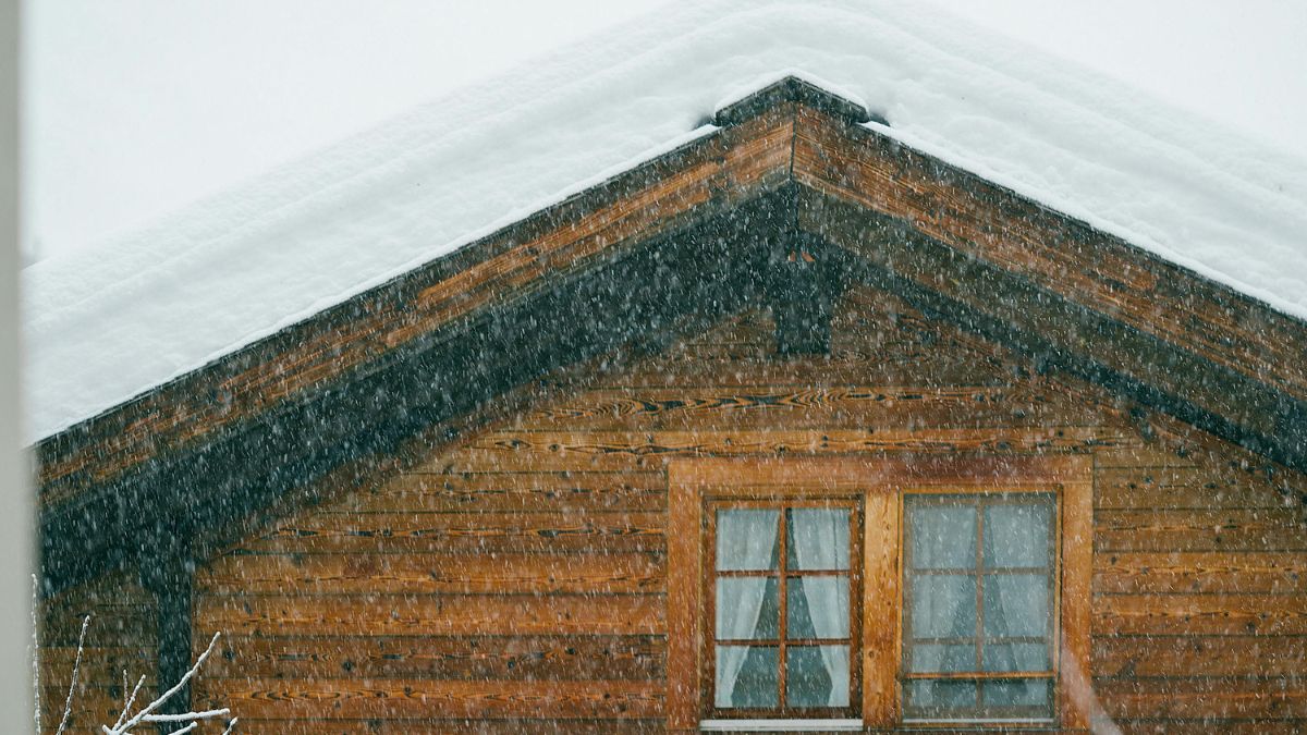 Wooden House with Roof Completely Covered in Snow - Winter Roof Replacement