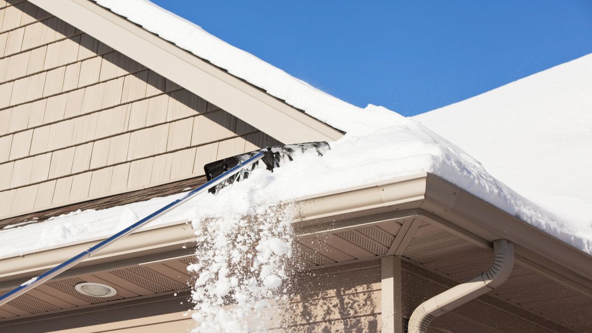 Illinois homeowner clearing snow from a roof, emphasizing the importance of roof maintenance after a snowstorm